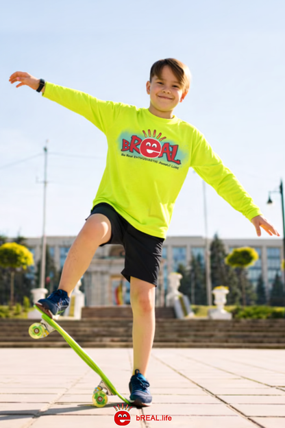 Child in a bright yellow shirt with 'bReal' logo on a skateboard outdoors.